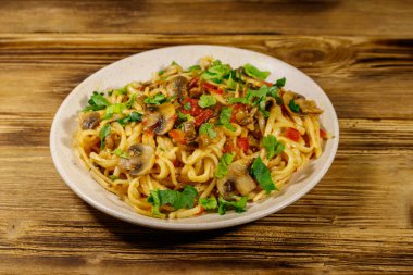 Mantarlı makarna ve ahşap masada domates sosu.