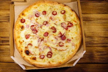 Tahta bir masanın üzerindeki karton kutuda nefis taze pizza. Üst Manzara. Yemek teslimatı, fast food, pizza teslimatı.