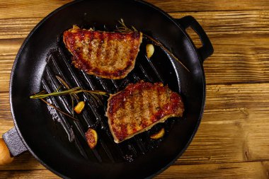 Biberiyeli ızgara domuz bifteği, sarımsak ve ahşap masada ızgara demir tavada baharat. Üst görünüm