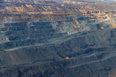 Çalışan çöp kamyonları ve kazıcıları olan dev bir demir cevheri ocağı.