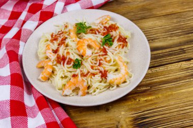 Karidesli makarna, domates sosu ve ahşap masada maydanoz.