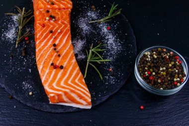 Çiğ somon fileto ve siyah tahtada baharat.