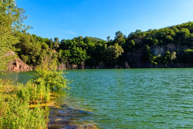 Yazın terk edilmiş taş ocağında göl manzarası