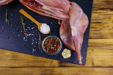 Ahşap masanın üzerinde siyah bir tahta üzerinde baharatlı çiğ tavşan eti. Üst görünüm