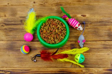 Kedi ve kase için tahta arka planda ev hayvanı yiyeceği olan oyuncaklar. Hayvan bakımı konsepti