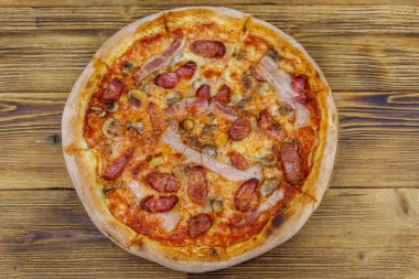 Ahşap bir masada sosisli, mantarlı ve peynirli lezzetli taze pizza. Üst görünüm