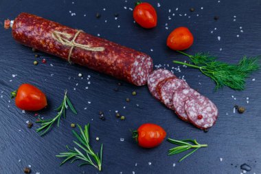 Siyah tahta üzerinde vişneli domates ve baharatlı salam sosisi. Üst görünüm