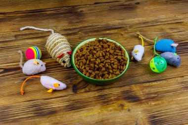 Kedi ve kase için tahta arka planda ev hayvanı yiyeceği olan oyuncaklar. Hayvan bakımı konsepti