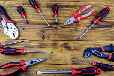 Tahta arka planda farklı pense ve tornavidalar var. Üst görünüm, alanı kopyala