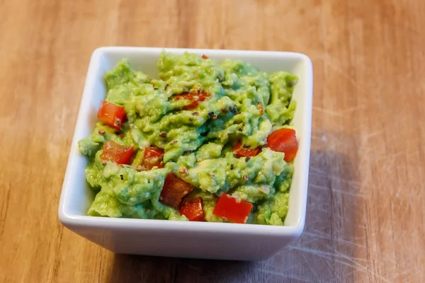 Tahta bir masada bir kase guacamole.