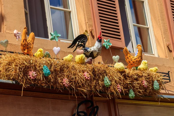 Easter decoration with rooster, hens and chickens in a nest on a house