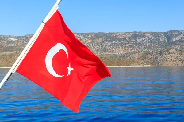 Red Turkish flag waving over the Mediterranean sea in Turkey