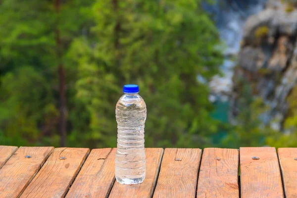 Plastikowa Butelka Świeżą Wodą Pitną Drewnianym Stole Tle Natury — Zdjęcie stockowe