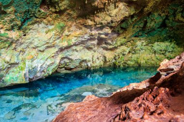 Kayalık bir mağarada dikitler ve dikitlerle oluşmuş güzel bir kristal berrak su havuzu manzarası. Tanzanya, Zanzibar 'daki Kuza mağarası