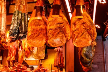 Jamon Serrano jambon bacakları geleneksel bir İspanyol pazarında sallanıyor.