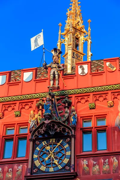 Close-up of red town hall with clock, paintings and ornaments in Basel, Switzerland