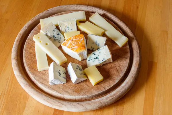 stock image Cheese platter with different kinds of cheese on wooden table