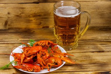Haşlanmış kerevit ve bir kupa bira ahşap masada.