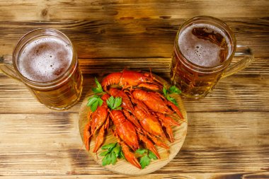 Haşlanmış kerevit ve tahta bir masada iki kupa bira.