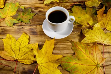 Bir fincan kahve ve sonbahar akçaağaç yaprakları ahşap masada. Sonbahar konsepti