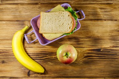 Sandviç, muz ve elmayla dolu bir beslenme çantası. Üst görünüm