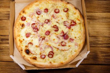 Tahta bir masanın üzerindeki karton kutuda nefis taze pizza. Üst Manzara. Yemek teslimatı, fast food, pizza teslimatı.