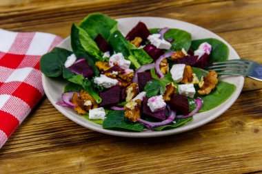 Haşlanmış pancar, peynir, ceviz ve ahşap masada kırmızı soğanlı ıspanak salatası. Sağlıklı vejetaryen yemekleri