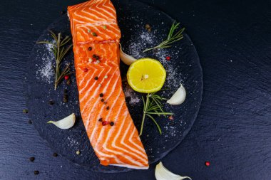 Çiğ somon fileto ve siyah tahta üzerinde baharat. Üst görünüm