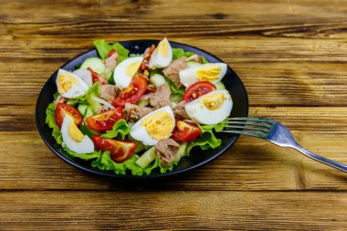 Yumurtalı lezzetli ton balığı salatası, marul ve ahşap masada taze sebze.