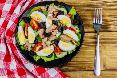 Marullu lezzetli ton balığı salatası, siyah zeytin, yumurta ve ahşap masada taze sebzeler. Üst görünüm