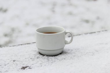 Kışın karlı bir masada bir fincan kahve.