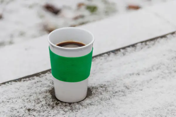 Cup of coffee on a snow covered table at winter