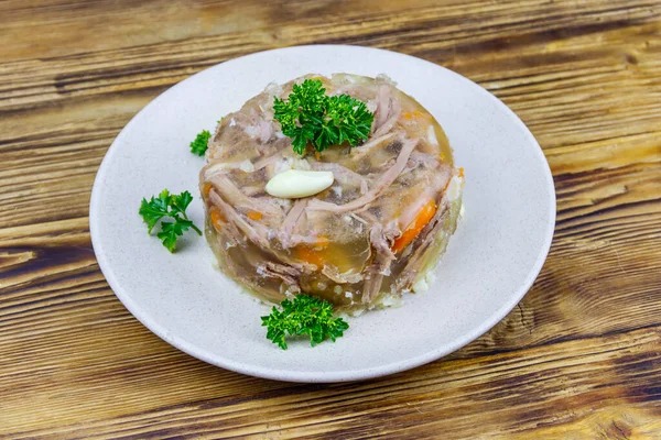 Meat aspic in a plate on a wooden table. Traditional russian dish