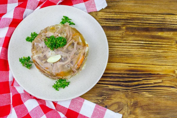 Meat aspic in a plate on a wooden table. Top view. Traditional russian dish