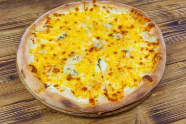 Tahta arka planda dört peynirli pizza.