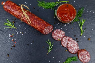 Ketçaplı salam sosisi ve siyah tahtada baharatlar. Üst görünüm