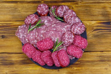 Ahşap masadaki siyah tahtada farklı bir dilimlenmiş salam sosisi. Üst görünüm