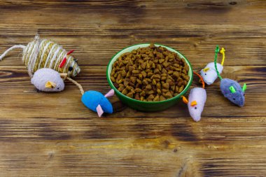 Kedi ve kase için tahta arka planda kuru hayvan mamasıyla fare oyuncakları. Hayvan bakımı konsepti