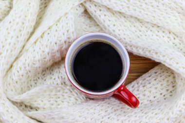 Etrafında beyaz örülü eşarp olan bir fincan kahve. Üst Manzara. Kış konsepti