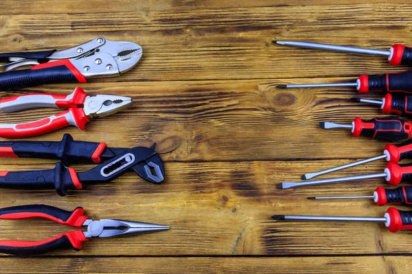 Tahta arka planda farklı pense ve tornavidalar var. Üst görünüm, alanı kopyala