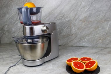 Mutfak masasında modern elektrik sıkacağı ve greyfurt. Taze sıkılmış greyfurt suyu hazırlanıyor.