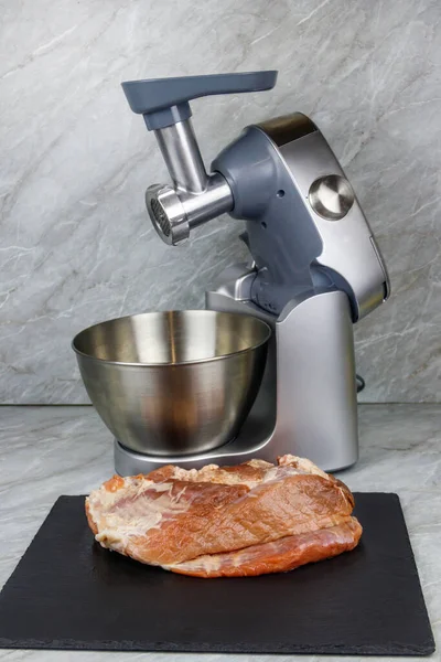 Electric eat grinder and fresh meat on kitchen table. Preparation of minced meat
