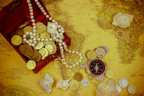 Treasure chest with jewelry and coins, compass and shells on a vintage map