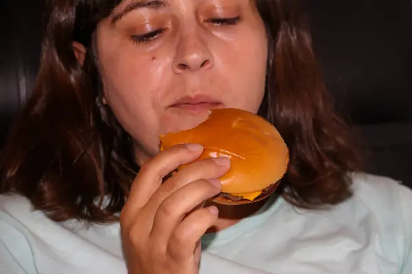 Caucasian woman eating tasty cheeseburger