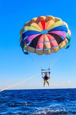 Parasailing su eğlencesi. Deniz kenarında bir yaz tatilinde bir teknenin arkasında paraşütle uçmak. Yaz tatili kavramı