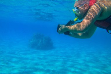 Fotoğraf makineli bir adam fotoğraf çekiyor ve Mısır 'da, Kızıl Deniz' de mercan resifi altında şnorkelle yüzüyor.