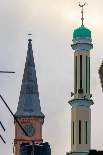 Christian church and minaret of the mosque side by side in Stone Town, Zanzibar, Tanzania