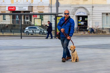 Kharkov, Ukrayna - 5 Nisan 2021: Ukrayna 'nın Kharkiv kentindeki Anayasa Meydanı' nda yürüyen labrador köpekli genç adam
