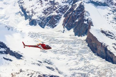 İsviçre 'deki karlı İsviçre Alpleri üzerinde uçan helikopter.