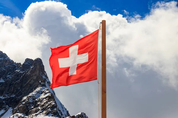 Red Swiss flag over the Swiss Alps background